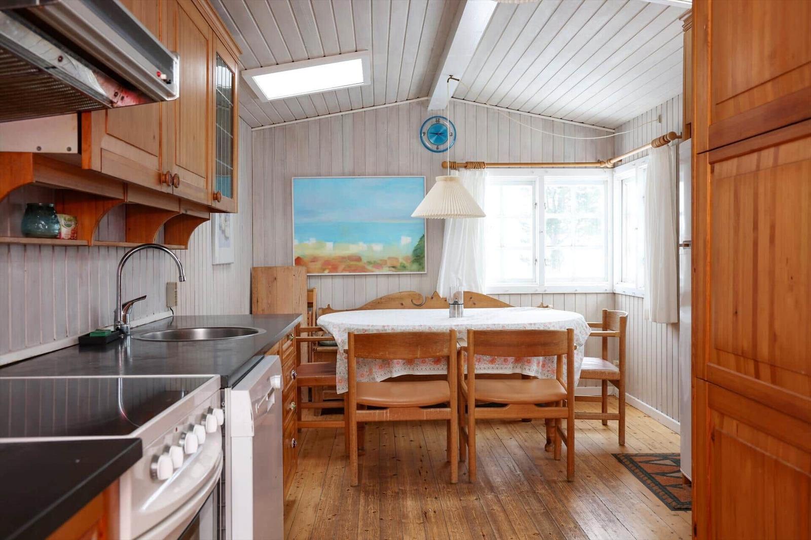Küche und Essbereich mit Holzmöbeln und Fenster. Tisch mit Tischdecke. Decke mit Licht.