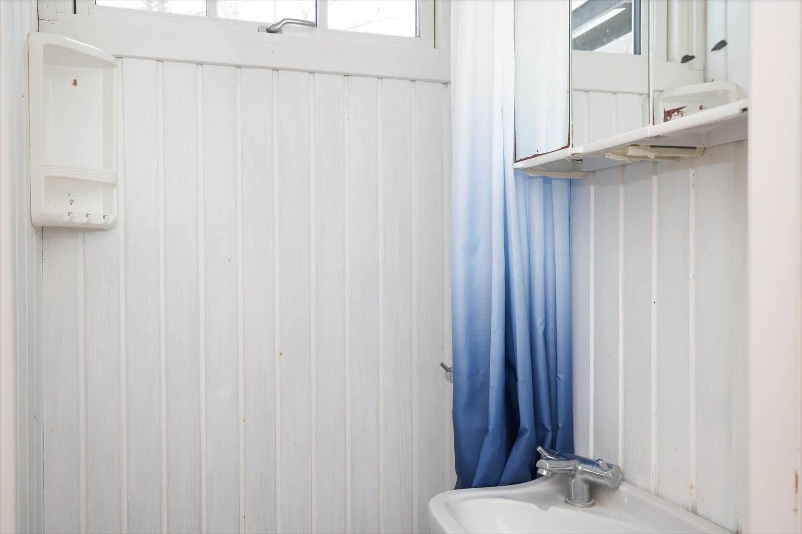 Badezimmer mit Waschbecken, blauer Duschvorhang und Spiegelschrank.