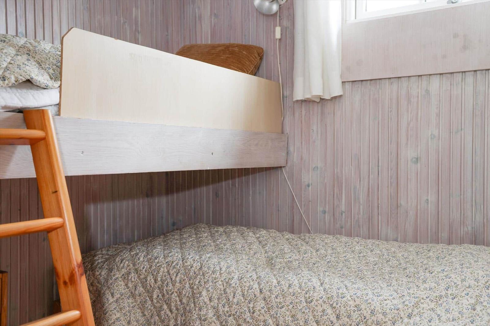Obere und untere Schlafcouch mit Holzgestell und floraler Bettwäsche.