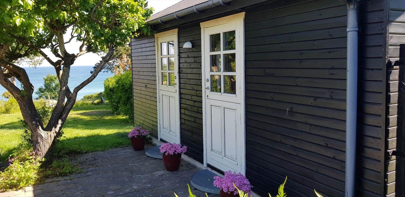 Haus mit zwei weißen Türen, Pflanzen und Blick aufs Meer.