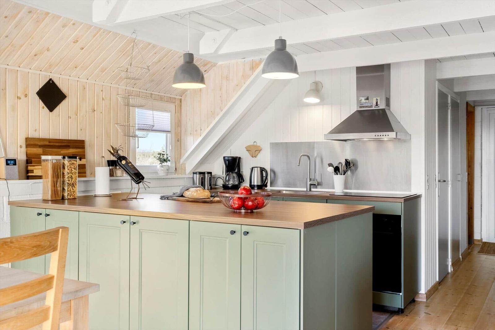 Küche mit grünen Schränken, Holzoberfläche und moderner Ausstattung unter Holzdecke.