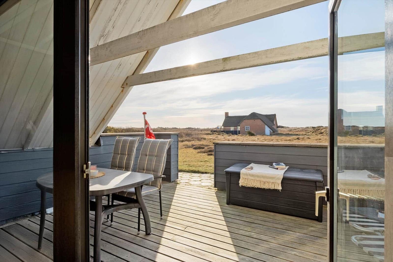 Terrasse mit Tisch, Stühlen und Blick auf das Feld und Haus.