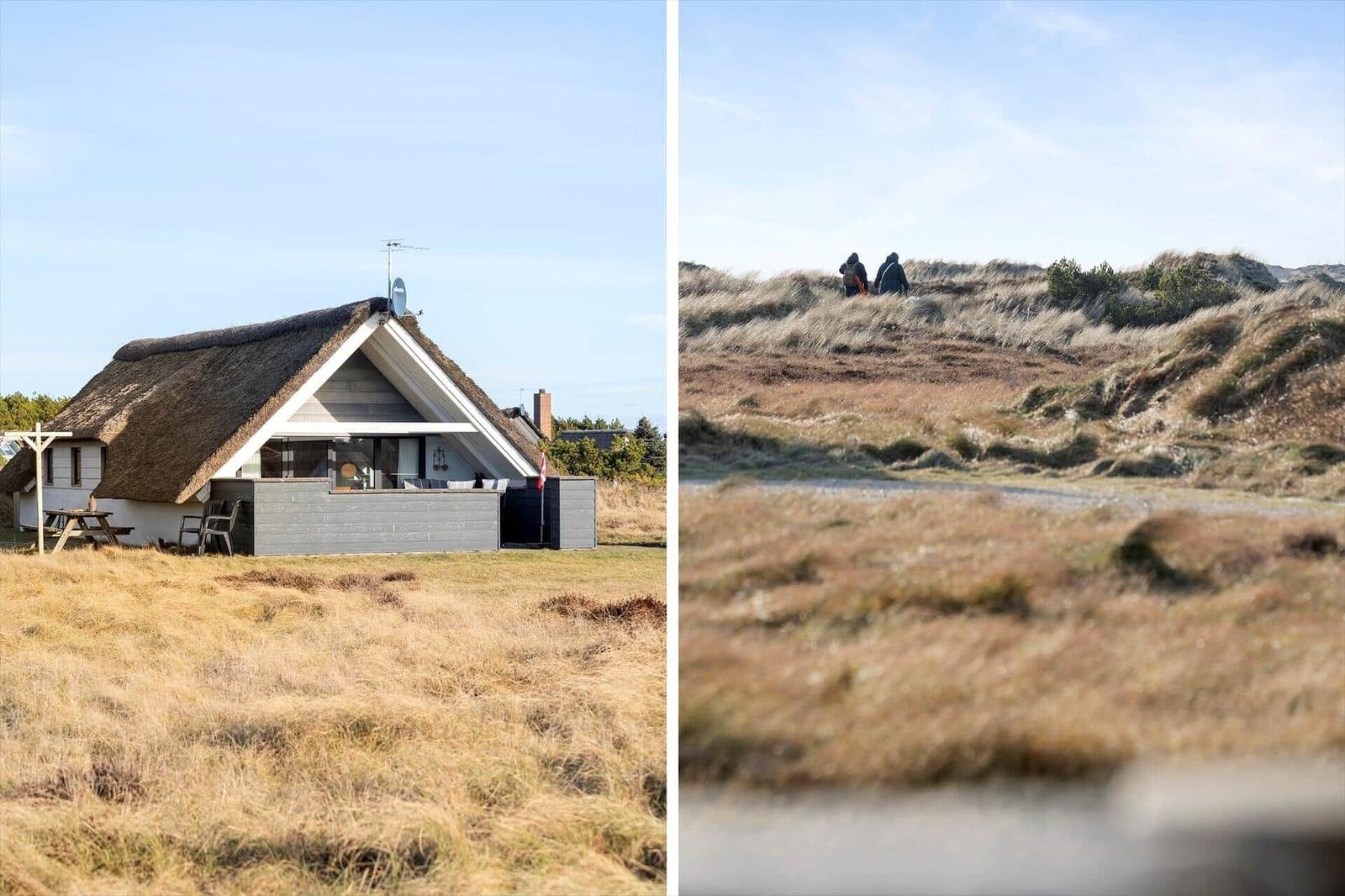 Haus mit Strohdach und Terrasse im Grasland. Zwei Personen wandern auf Dünen.