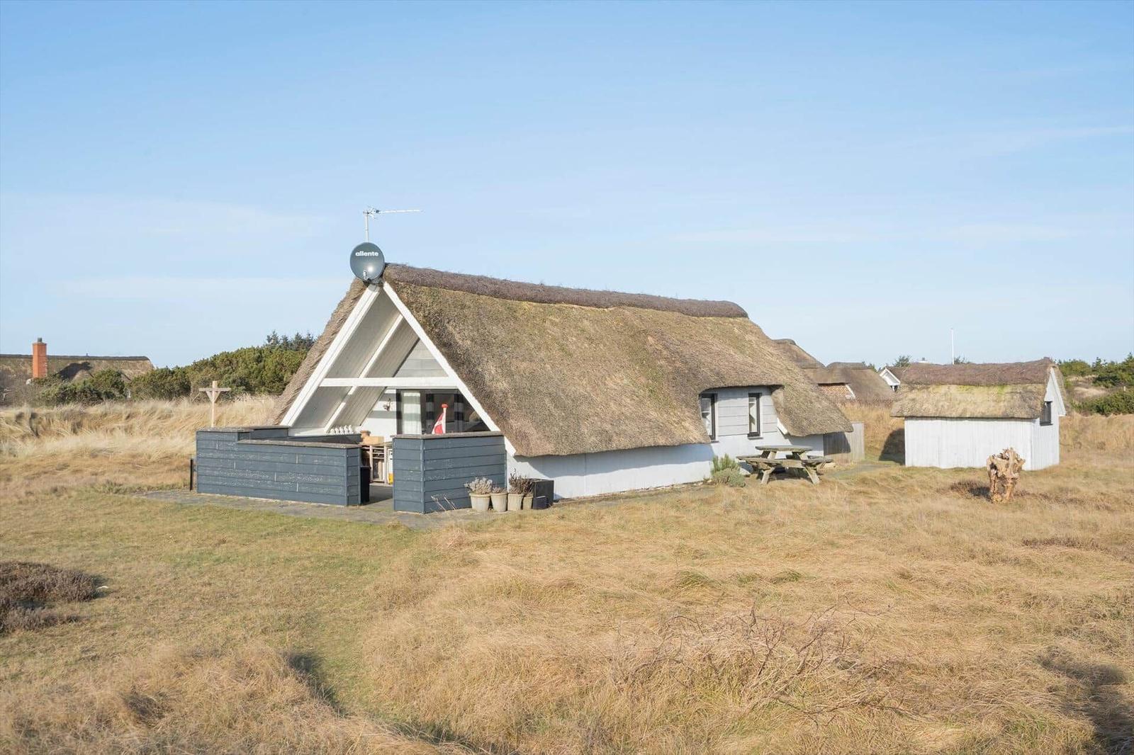 Dorfhaus mit Strohdach, Terrasse und Picknicktisch im Grasland