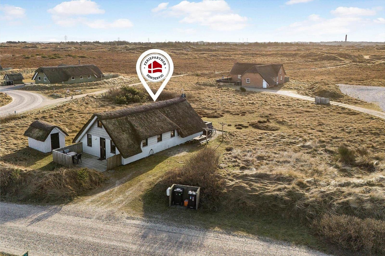 Dorfhaus mit strohgedecktem Dach in hügeliger Landschaft