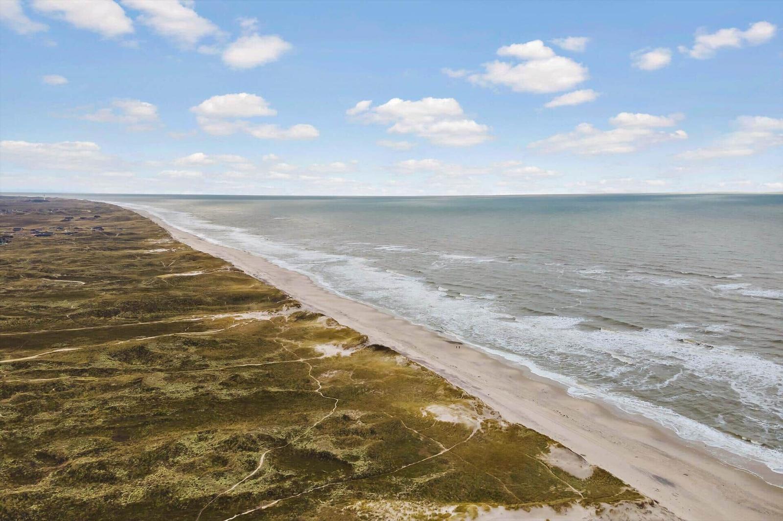 Aerielansicht einer Küstenlandschaft mit Strand und Wellen.