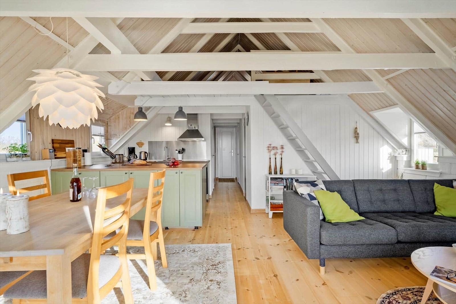 Wohn- und Essbereich mit Küchenzeile unter Holzdecke.