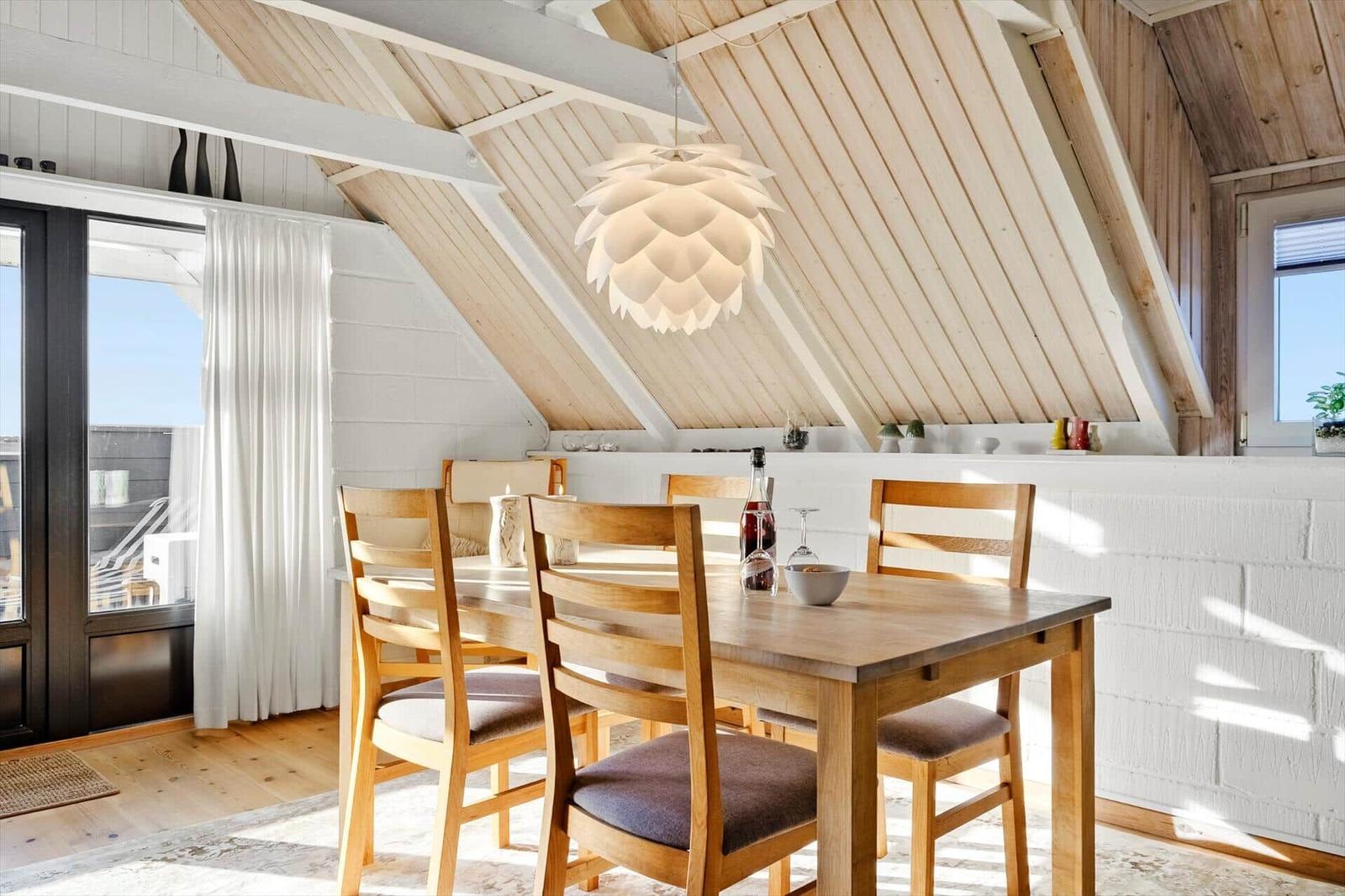 Essbereich mit Holztisch, Stühlen und Deckenleuchte unter Holzdach