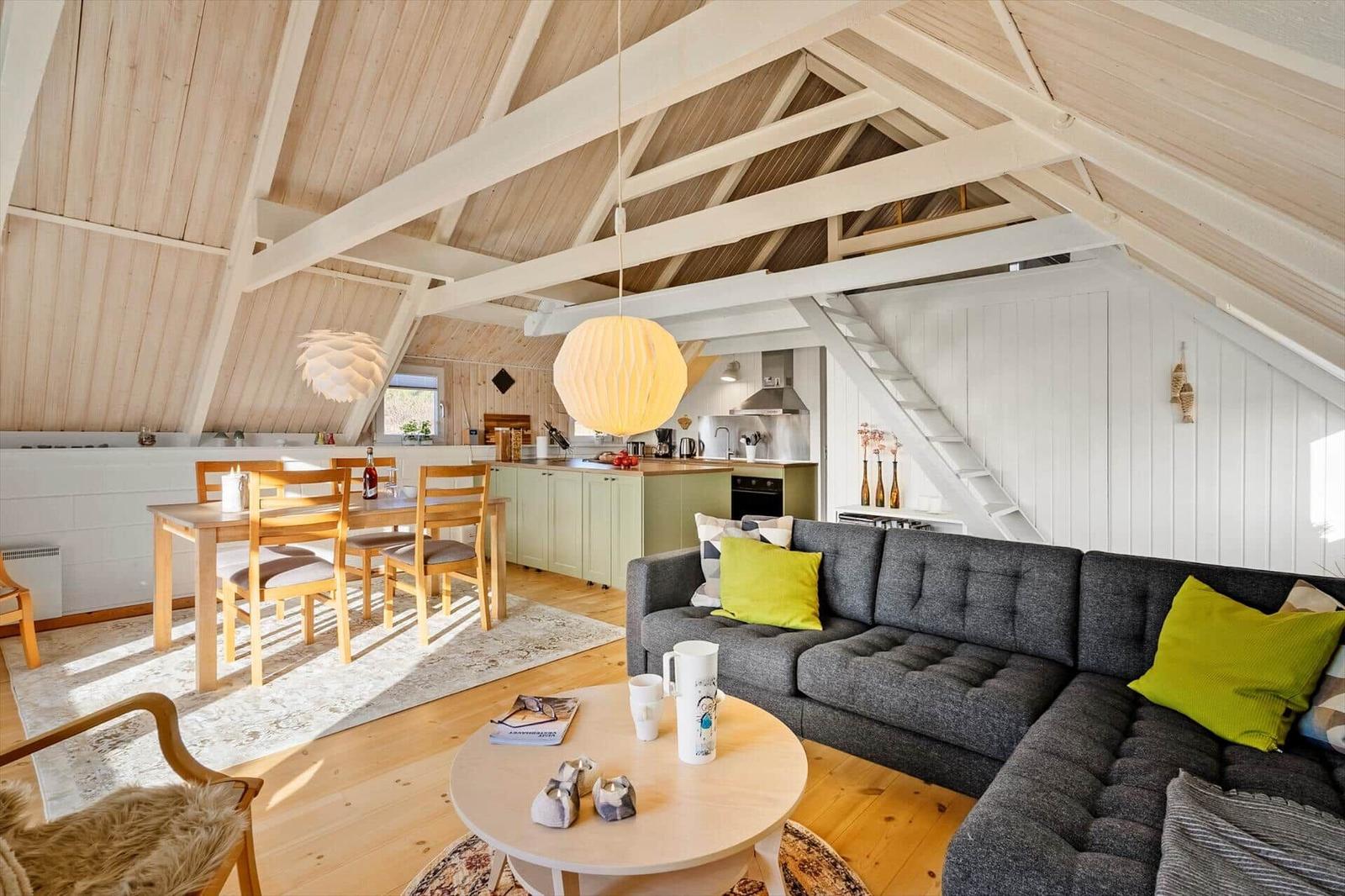 Wohnung mit Essbereich, Küche und Sofa unter Holzdecke.