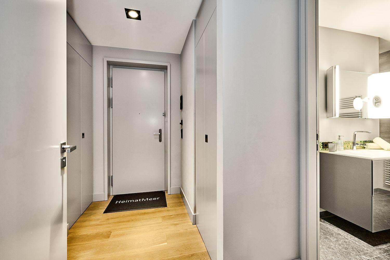 Flur mit Holzboden, Tür und Bad mit Waschbecken