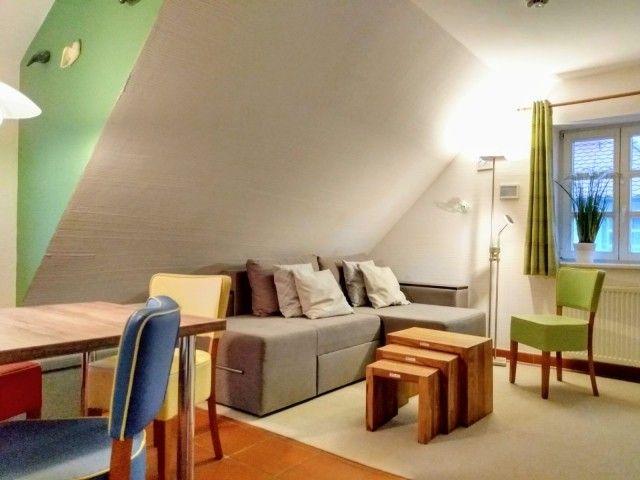 Wohnraum mit Sofa, Tisch und Stühlen unter Dachschrägen.