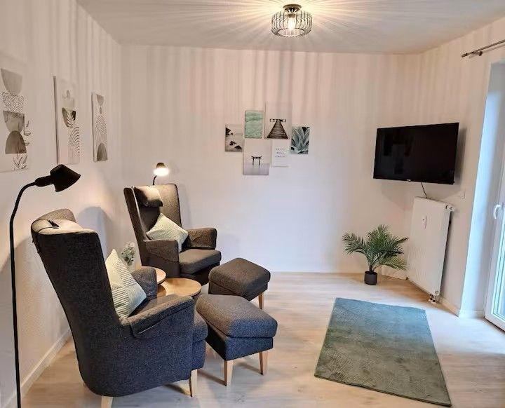 Wohnzimmer mit zwei Sesseln, Fernseher und Pflanze.