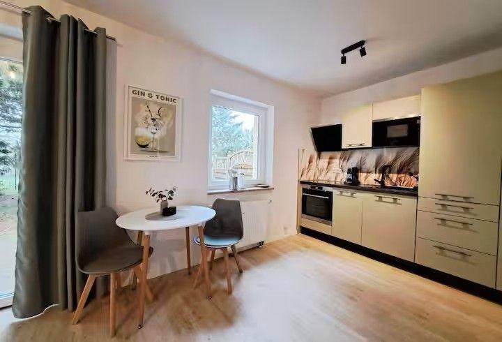 Küche mit Essbereich, Fenster, Küchenschränke und Deckenstrahler.