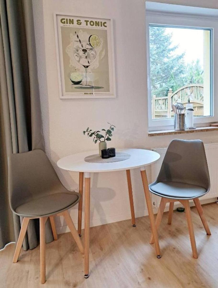 Rundtisch mit zwei Stühlen vor Fenster mit Gartenblick.