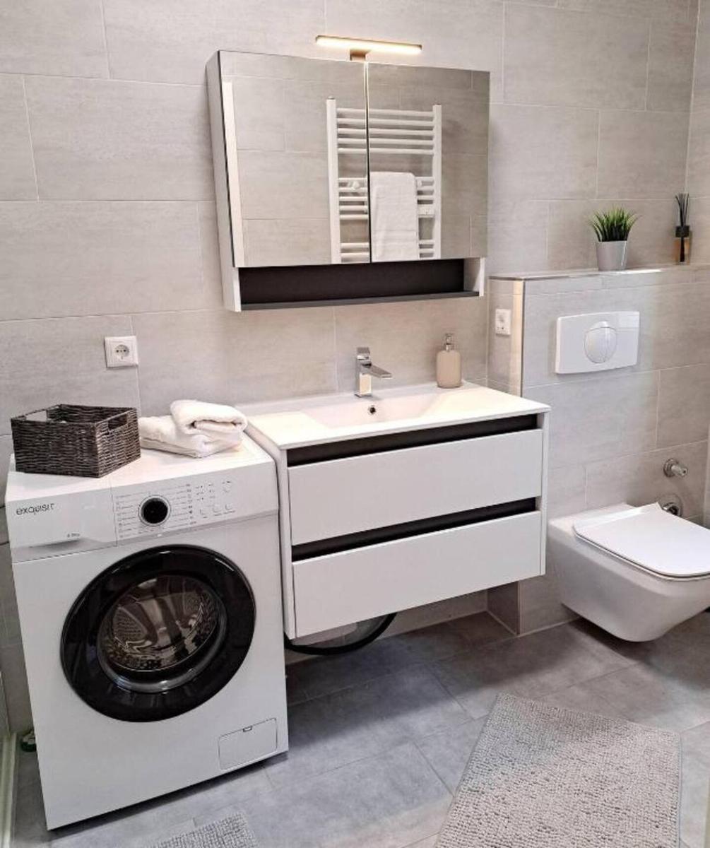 Badezimmer mit Waschmaschine, Spiegelschrank und Toilette