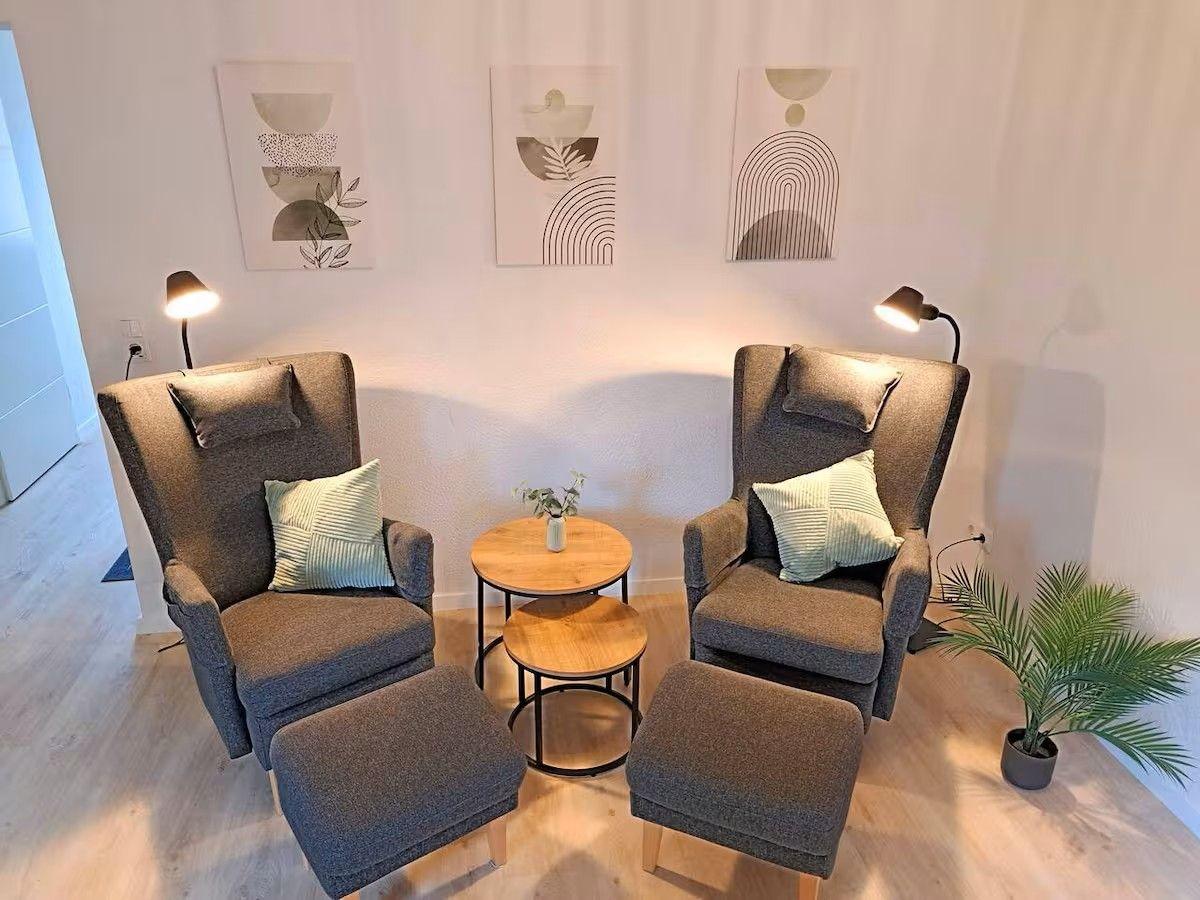 Zwei graue Sessel mit Fußhocker und kleinem Tisch