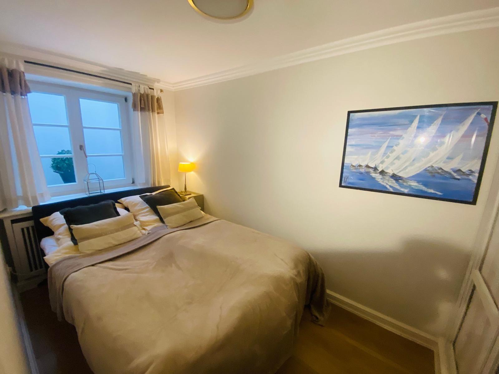 Schlafzimmer mit Bett, Fenster und Wandbild.