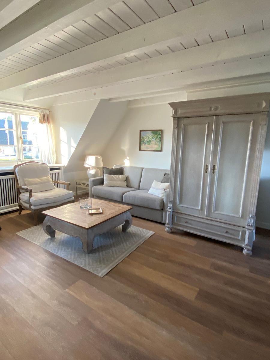 Wohnzimmer mit Sofa, Sessel, Kamin und Holzboden.