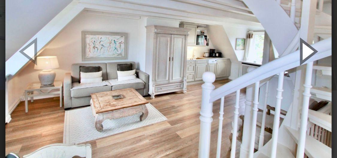 Wohnbereich mit Sofa, Couchtisch und Küchenbereich unter Dachschräge.