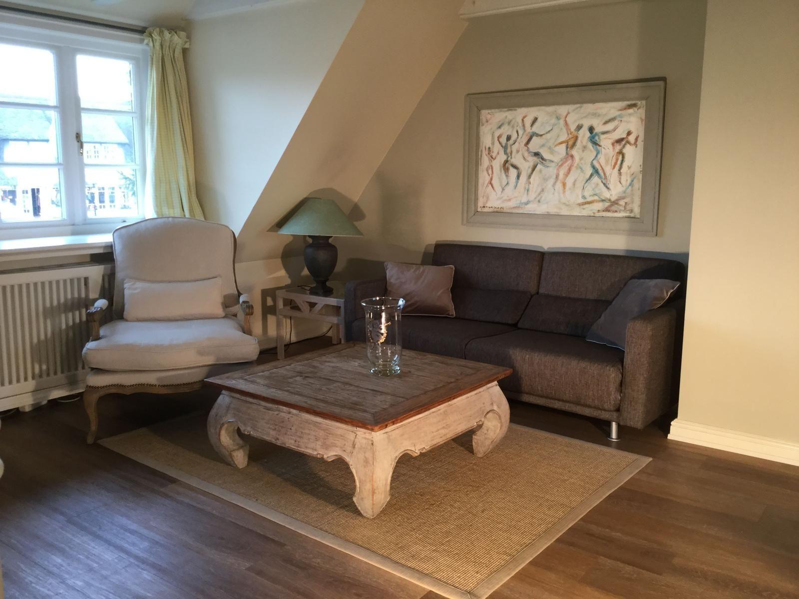 Wohnzimmer mit Sofa, Sessel und Holztisch unter Dachschräge.