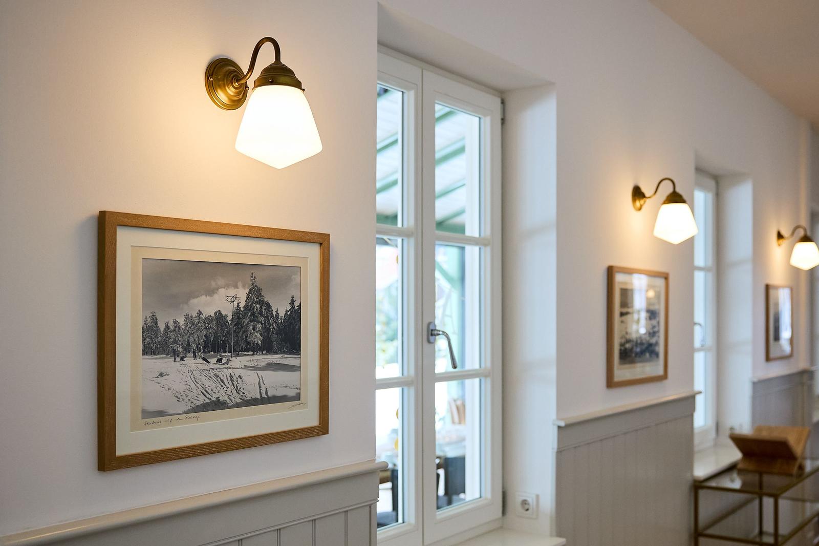 Flur mit Bildern, Lampen und Fenstern.