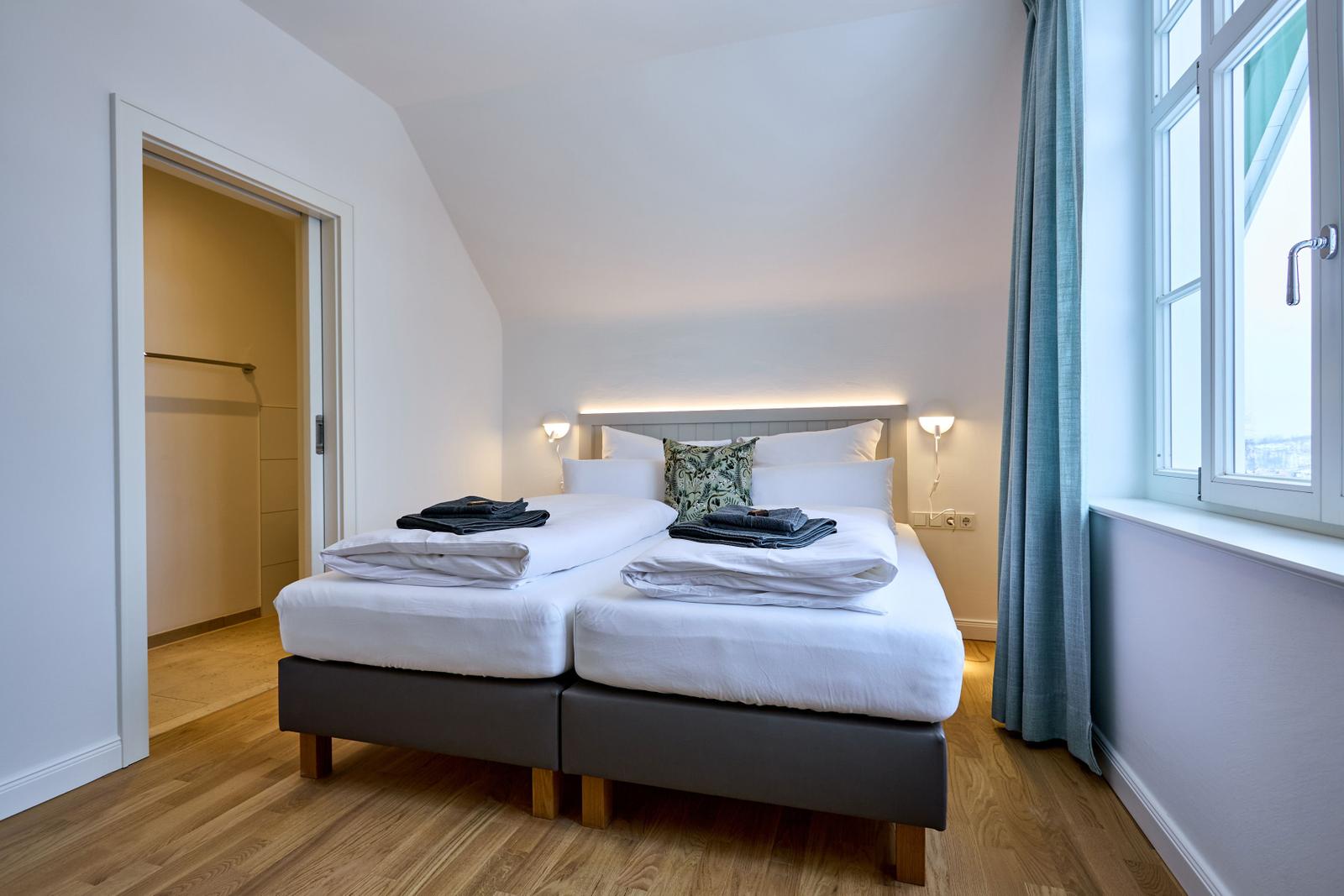 Schlafzimmer mit Doppelbett, Fenster und Kleiderschrank.