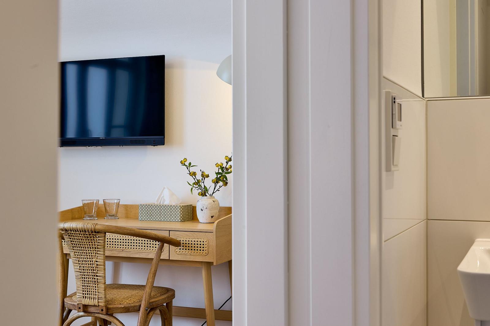 Schreibtisch mit Stuhl, Fernseher und Blumen