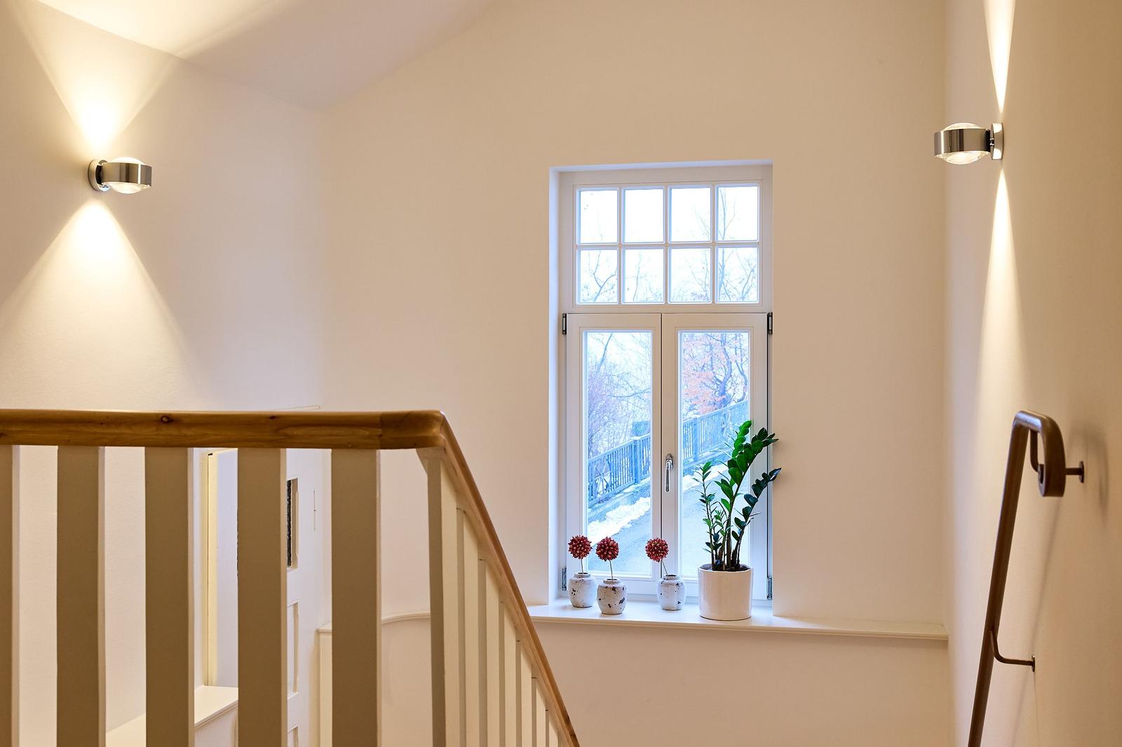 Hausflur mit Treppe, Fenster und Pflanzen auf dem Fensterbrett.