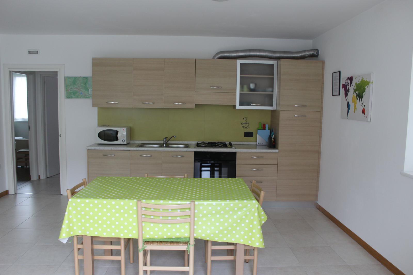 Küche mit Essbereich, grüner Tischdecke und Holzmöbel.