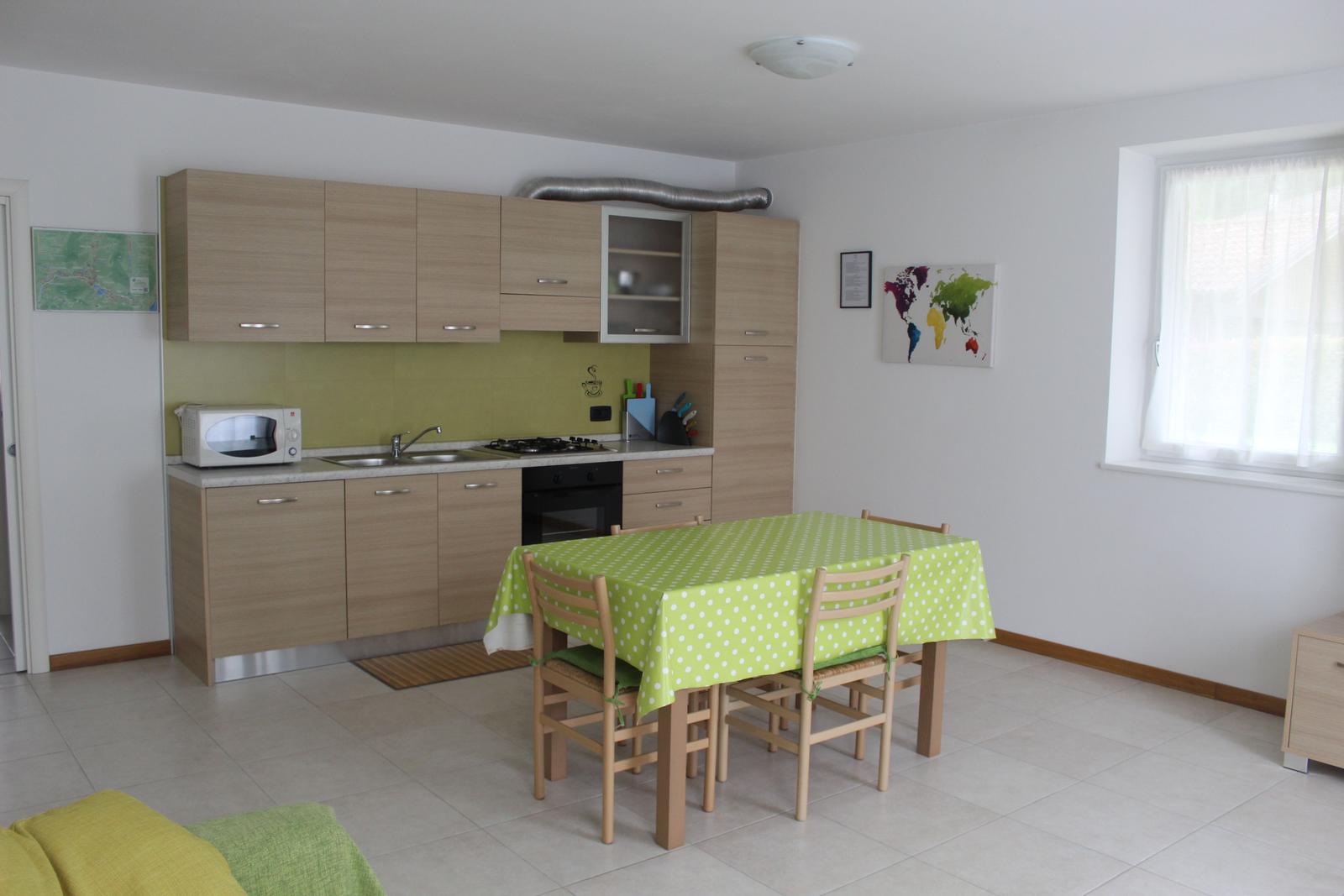 Küche mit Essbereich, grüner Tischdecke und Holzstühlen