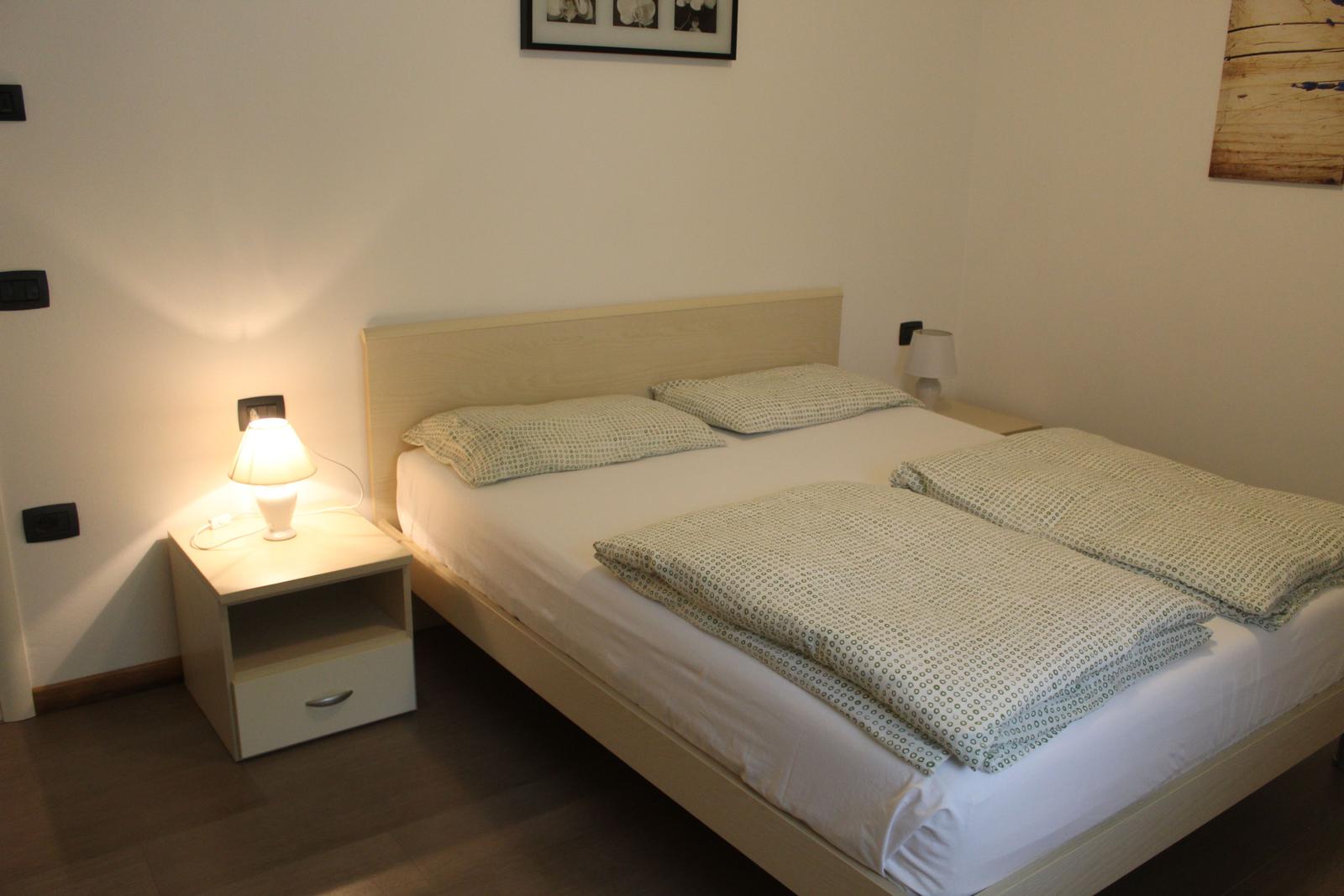 Schlafzimmer mit Doppelbett, Nachttisch und Wandbildern.