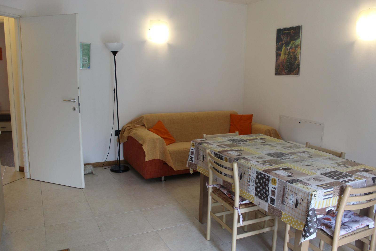 Wohn- und Essbereich mit Sofa, Tisch und Stühlen. Wandlampen und Wandbild.