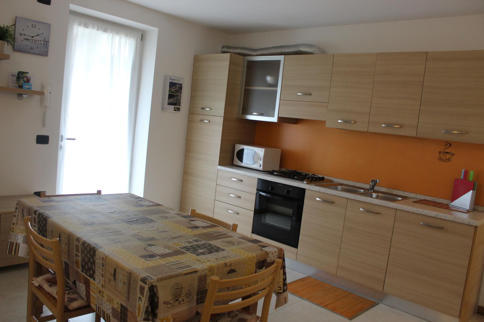 Küche mit Essbereich, Holztisch, Mikrowelle und Ofen