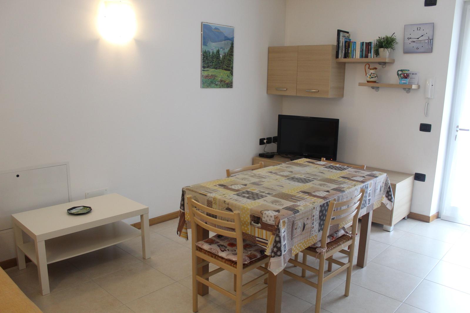 Esszimmer mit Tisch, Stühlen und Fernseher. Wandregale und Bild an der Wand.