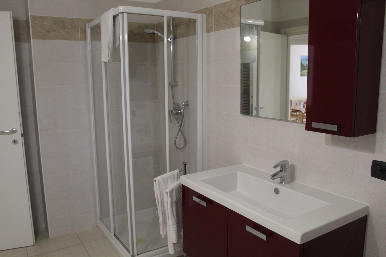 Bad mit Dusche, Waschbecken und Spiegel.