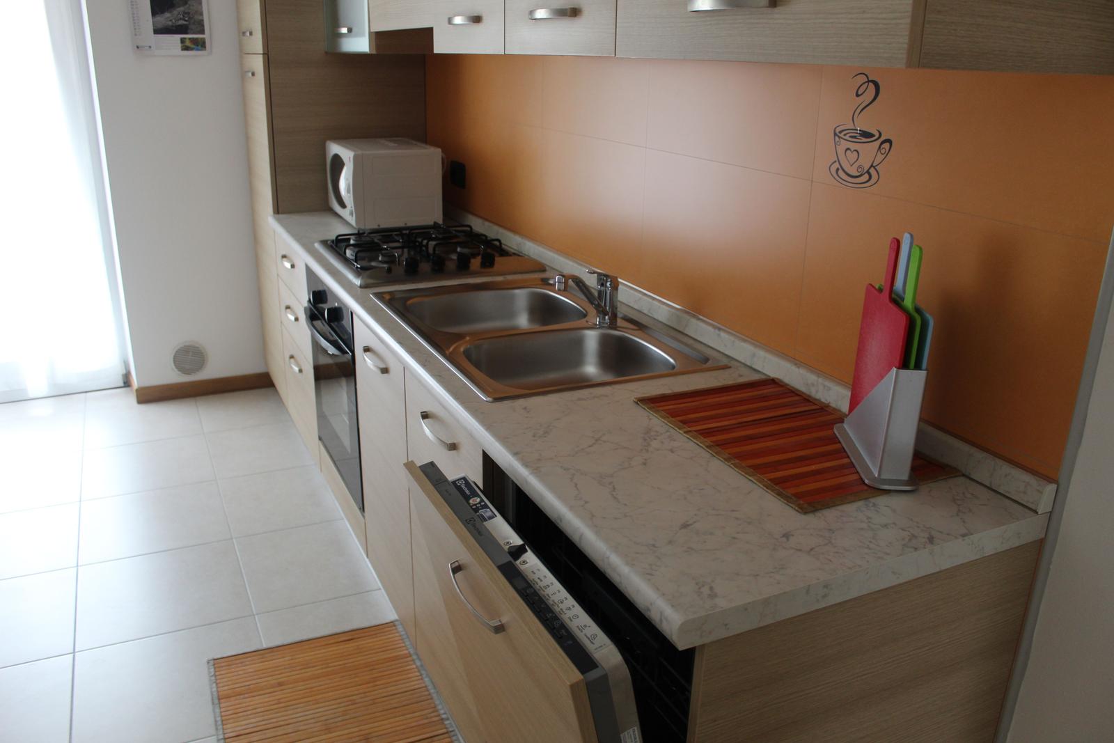 Küche mit Arbeitsplatte, Spüle, Herd und Mikrowelle.