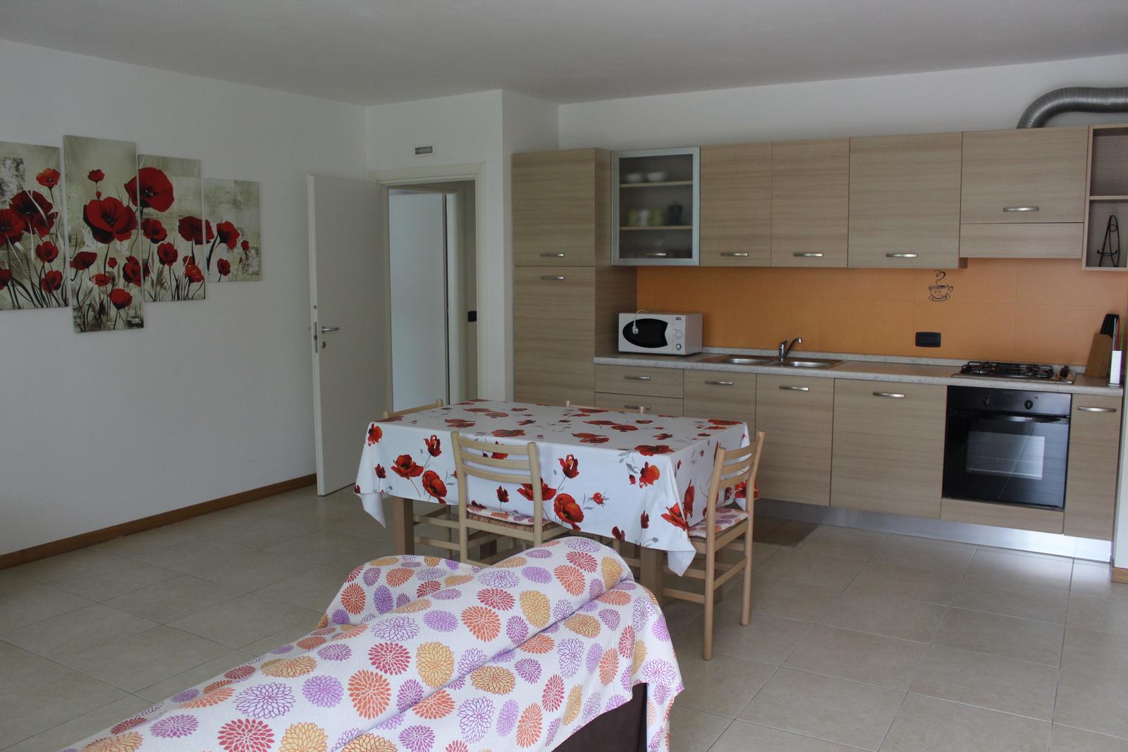 Küche mit Essbereich und Schlafplatz mit floralen Tischdecken.