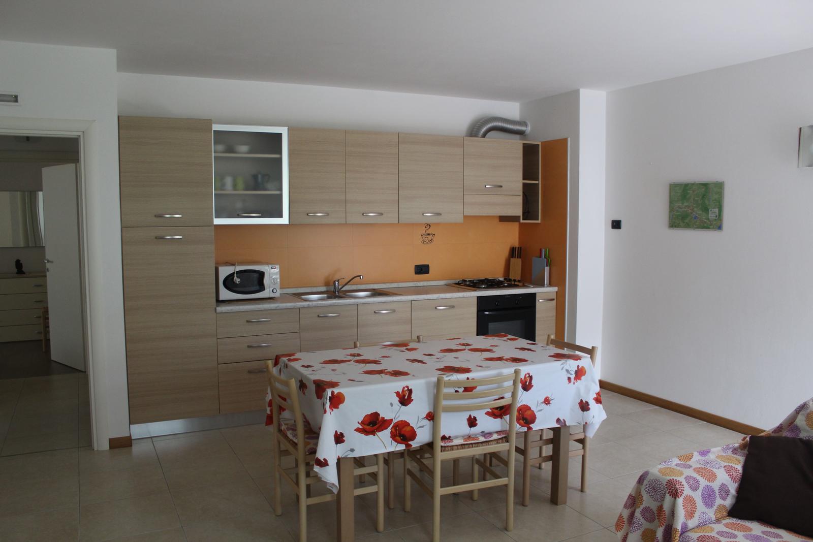 Küche mit Esstisch, Mikrowelle und Kochfeld.