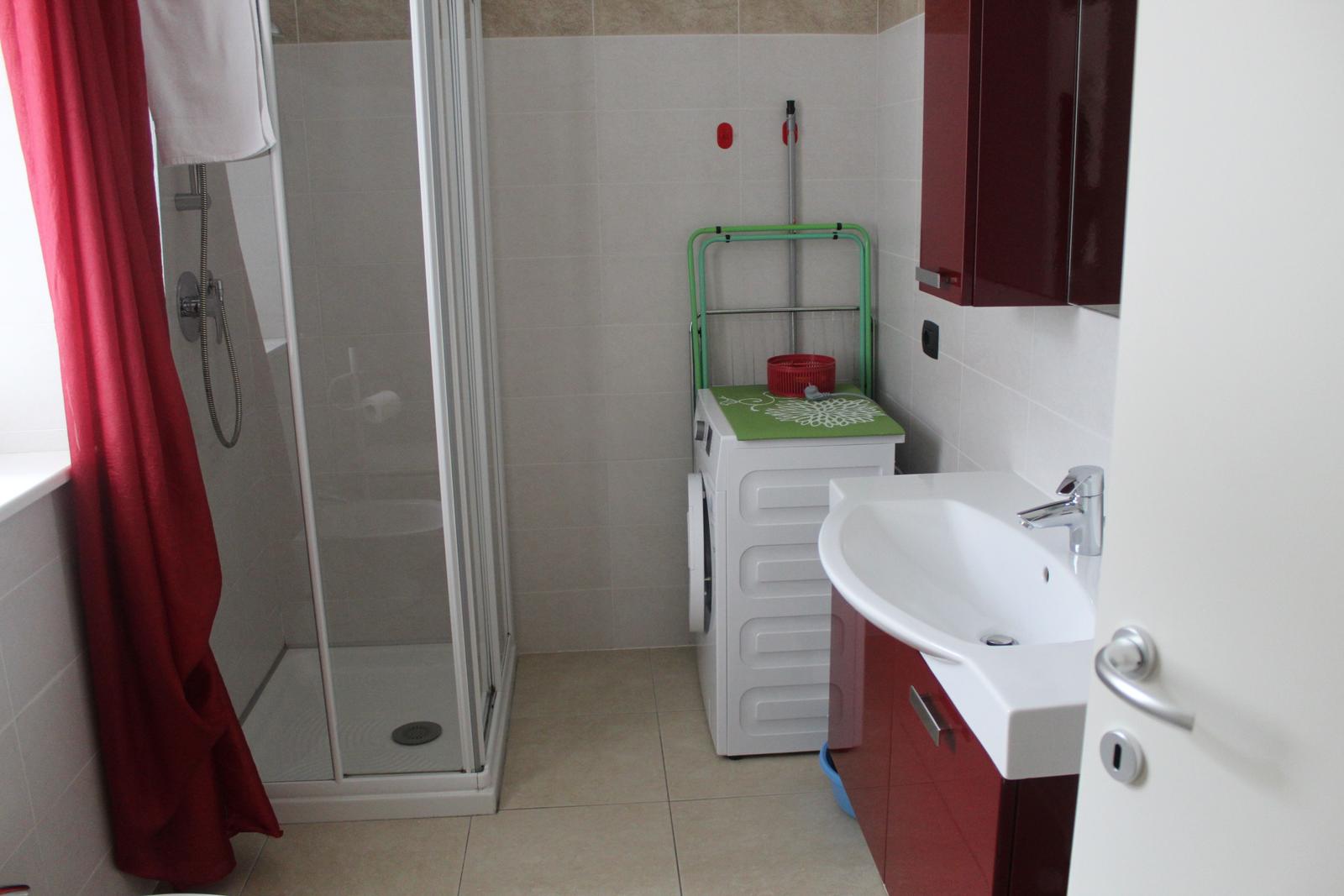 Badezimmer mit Dusche, Waschmaschine und Waschbecken