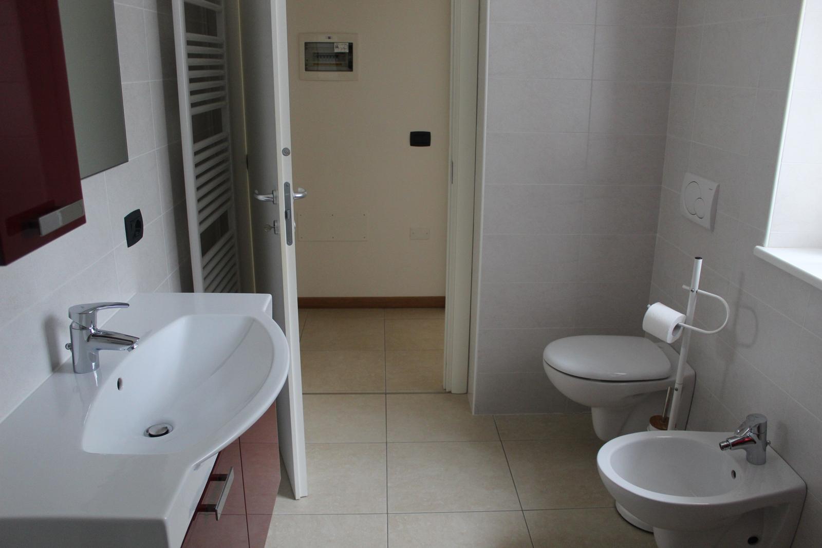 Badezimmer mit Waschbecken, WC und Bidet. Fliesenboden und Wandfliesen.