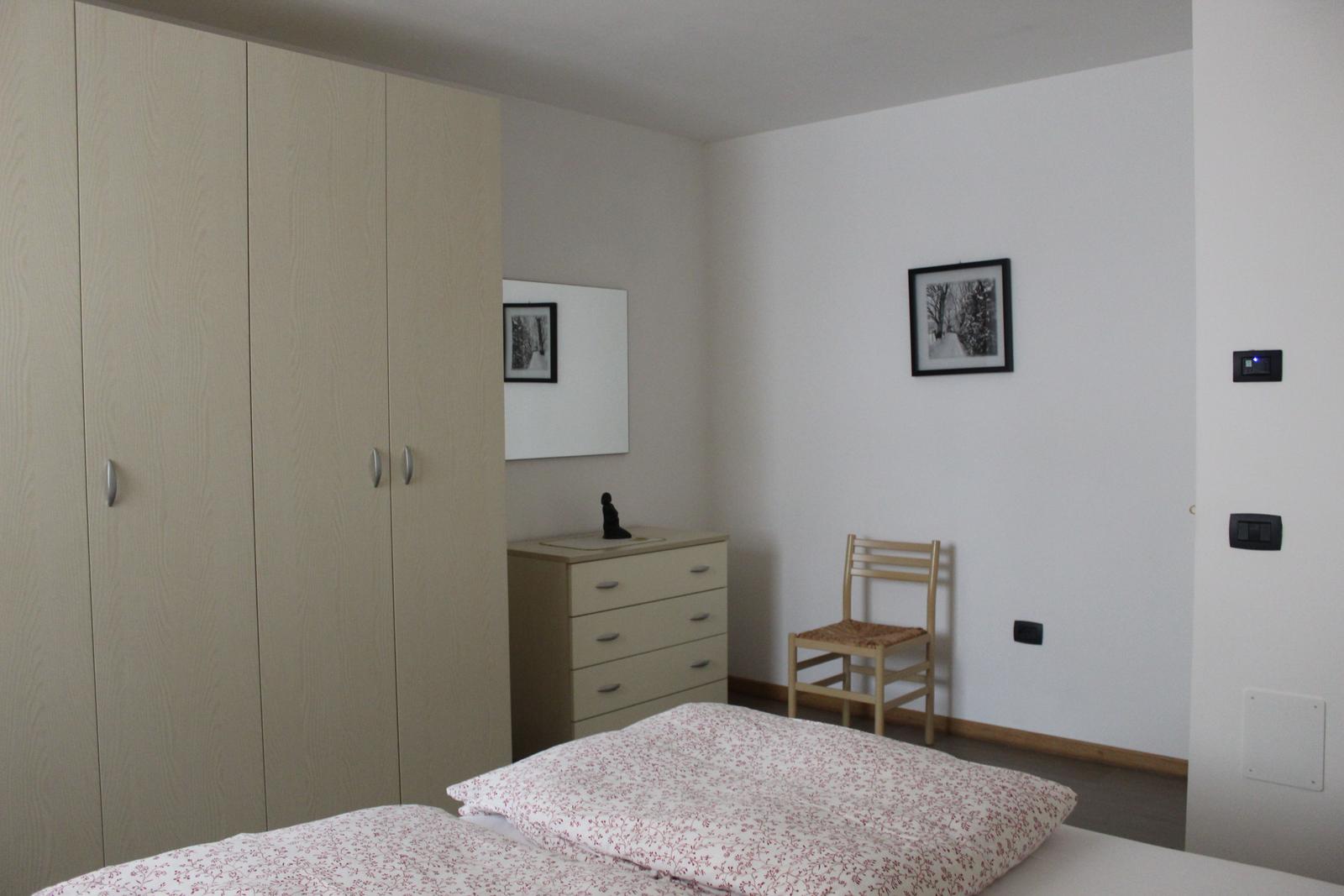 Schlafzimmer mit Bett, Kleiderschrank, Schreibtisch und Stuhl.