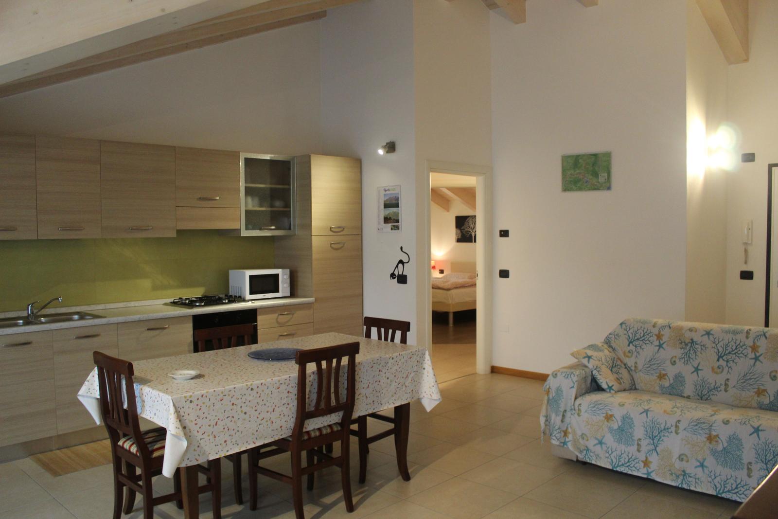 Küche mit Esstisch, Wohnbereich mit Sofa und Blick in Schlafzimmer.