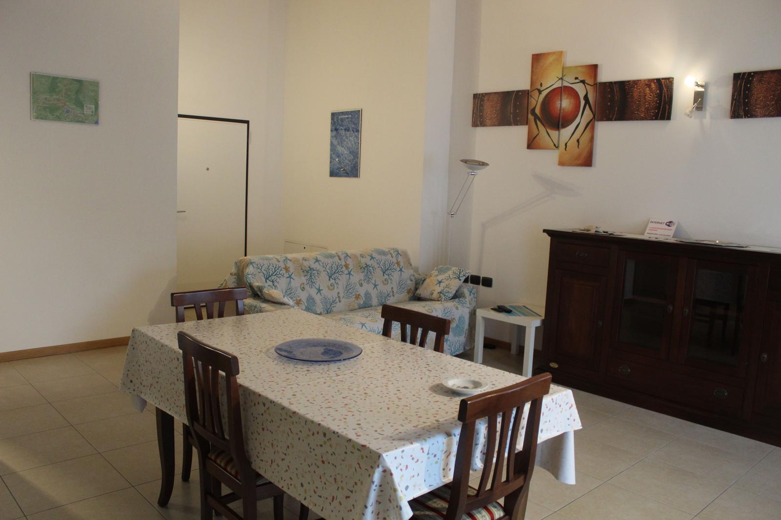 Essbereich mit Tisch, Stühlen und Sofa. Wanddekoration und Schrank sind sichtbar.