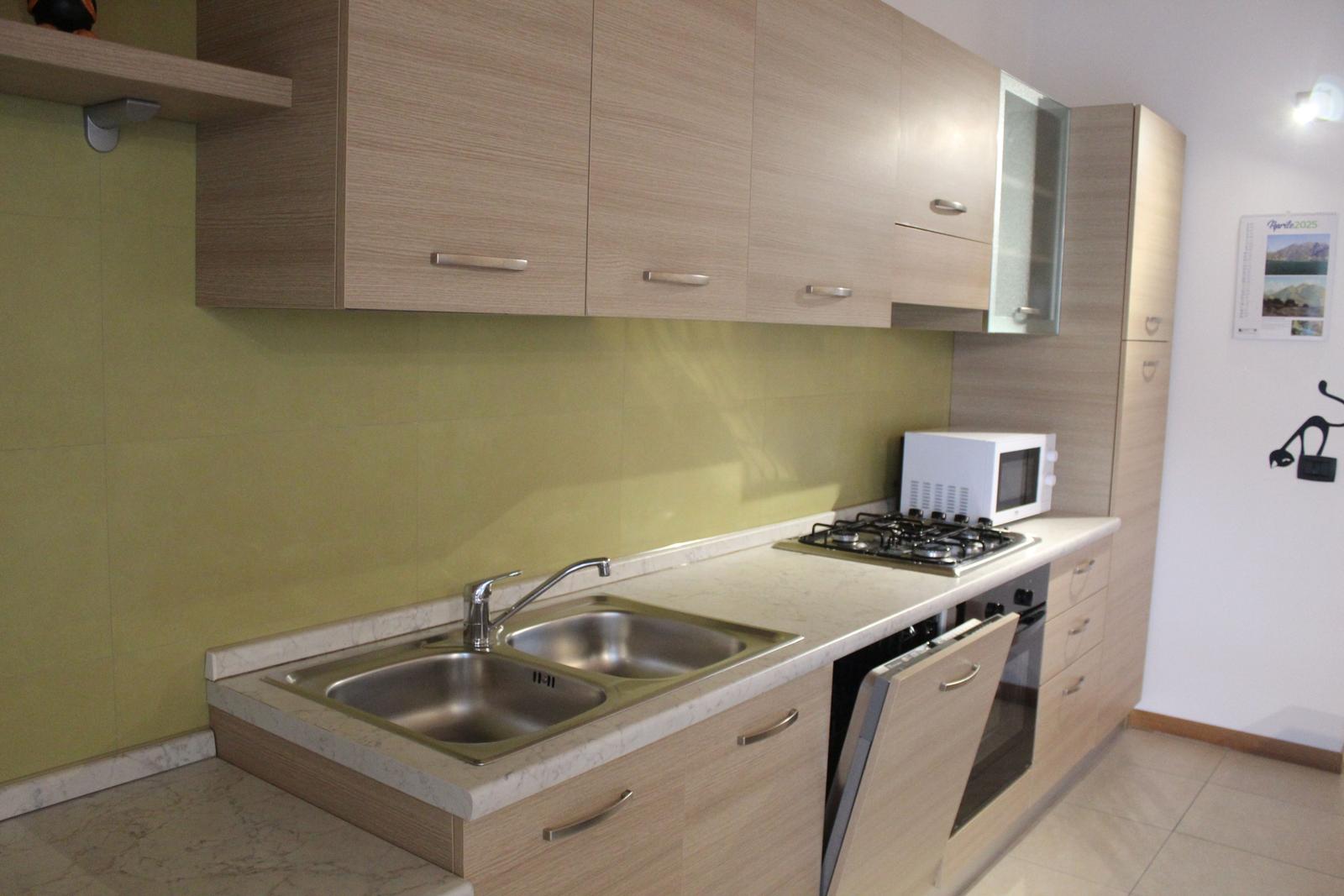 Küche mit Arbeitsplatte, Spüle, Herd und Mikrowelle.