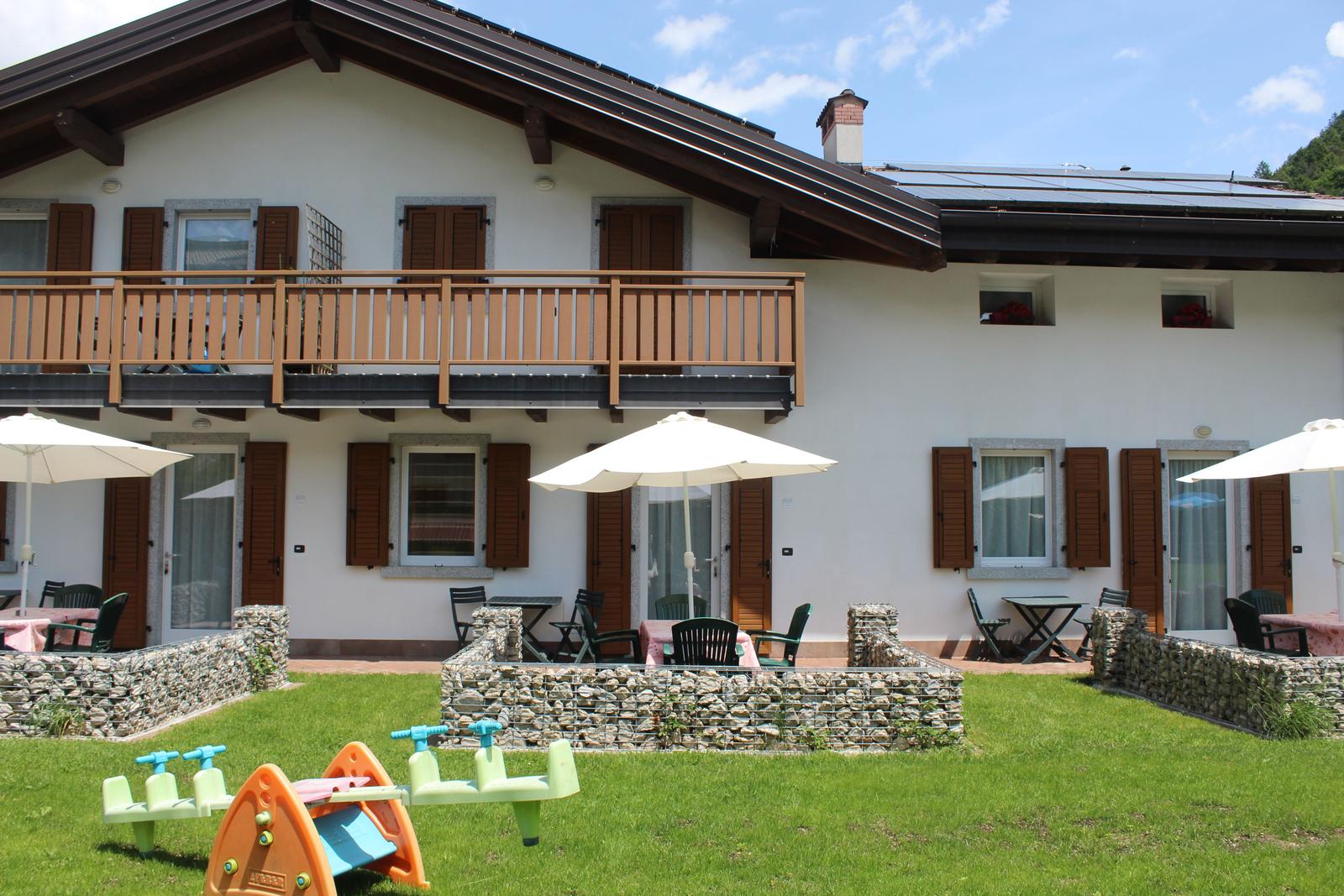 Haus mit Balkon, Terrasse und Spielplatz im Garten.