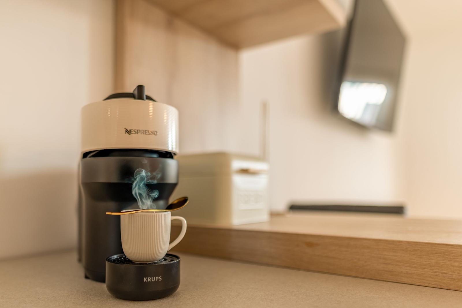 Nespresso coffee machine with steaming cup on kitchen counter