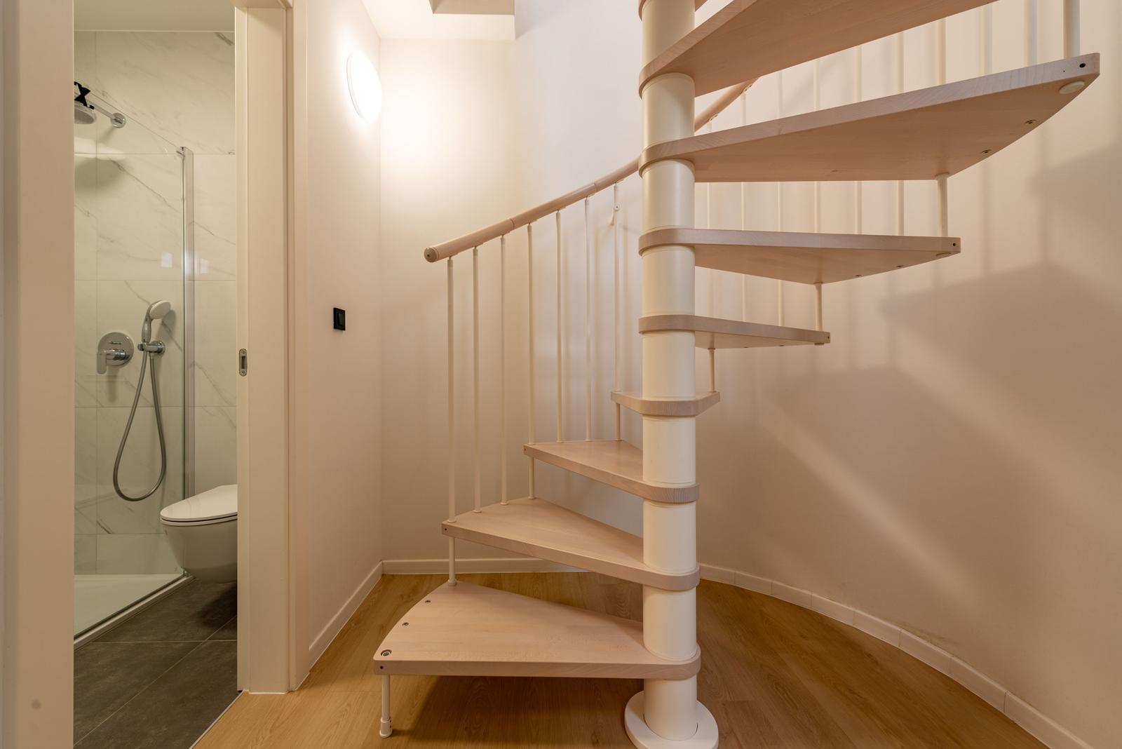 Spiral staircase leads to a shower and toilet.
