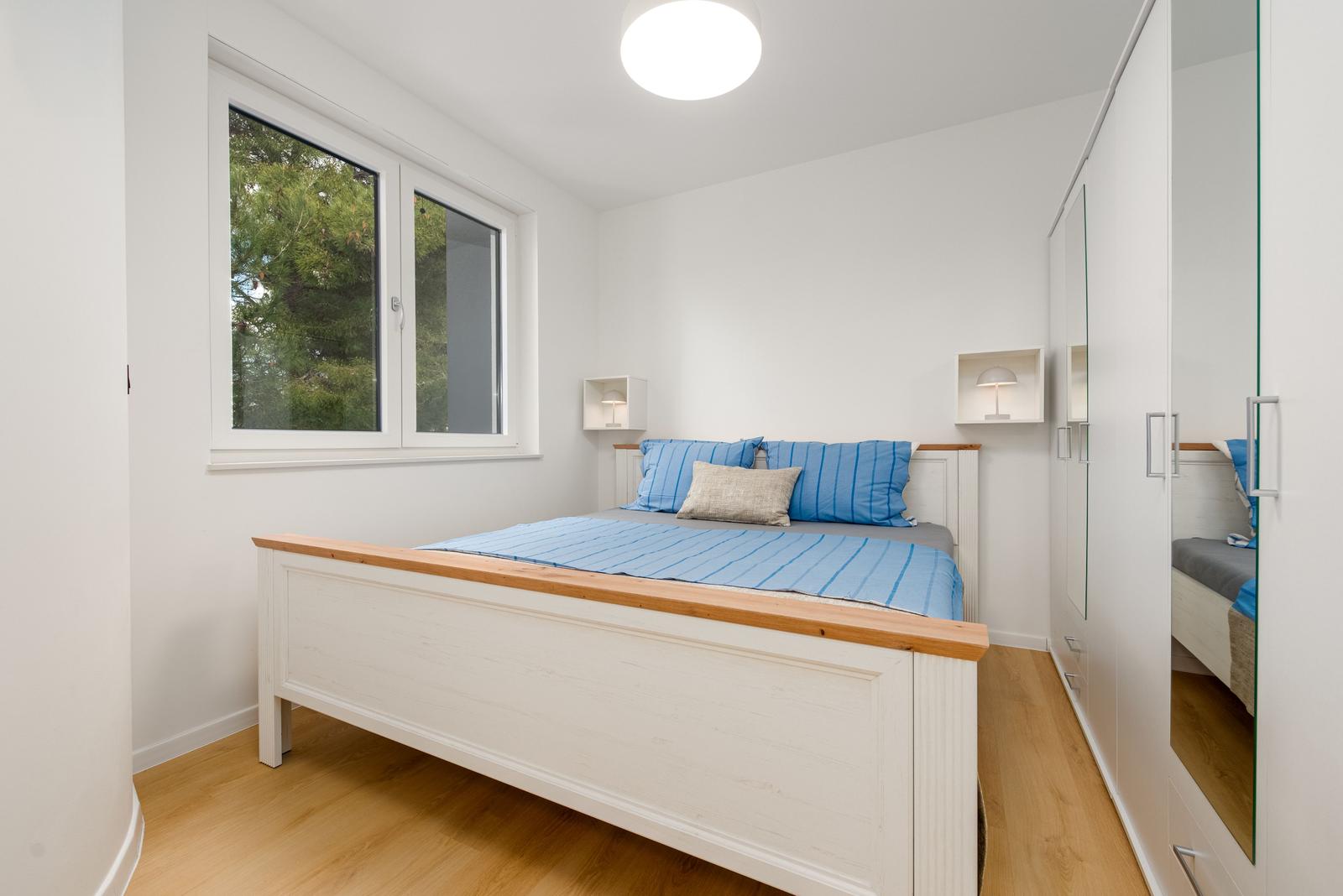 Bedroom with bed, window, and wardrobe.