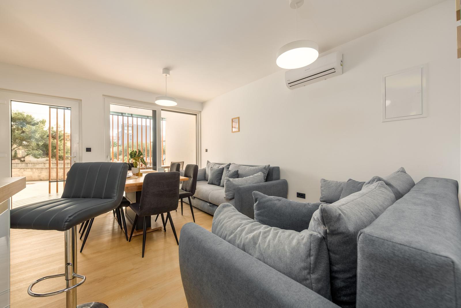 Living and dining area with sofa, table and chairs, view to balcony.