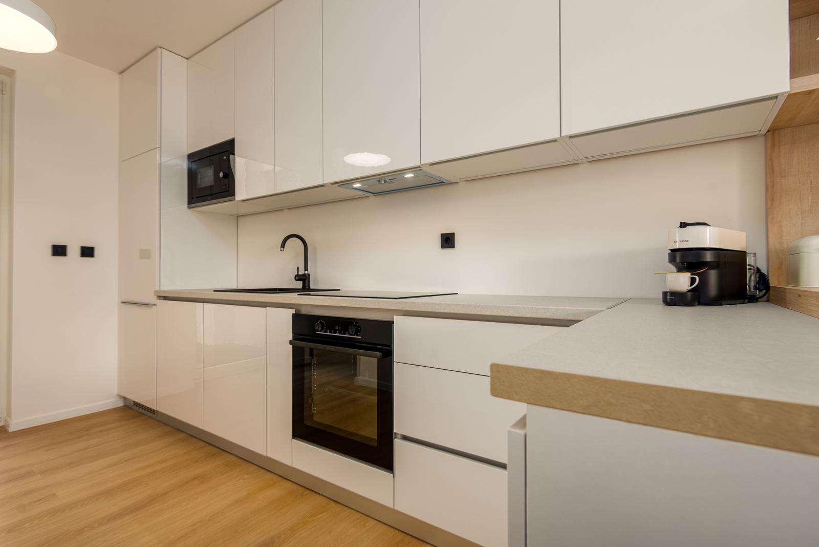 Modern kitchen with white cabinets, stainless steel countertop, and built-in oven.